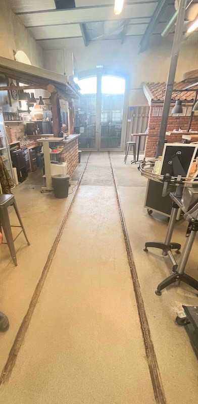 Interiör från nuvarande bryggeri/ destilleri med spåret i golvet. Riktning västerut =mot port och nedanför detta en slänt mot fd bangården