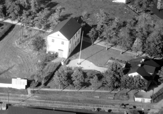 Foto (utsnitt) av O Liljekvist/ JvmKBFR00156. Samma förhållande här; transformatorhuset t v och stationshuset t h. Men här syns även husens fram/ kortsidor västerut. Och man kan ana att spåret inne i förstnämnda ”stack ut” en bit genom porten. Men det var alltså inte anslutet till något annat spår.